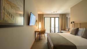 アテネにあるFos DownTown Suitesのベッドとデスクが備わるホテルルームです。