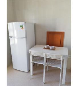 a white table and a refrigerator and a table and chairs at Mini appartamento Aria in OstuniCrispiHouse in Ostuni
