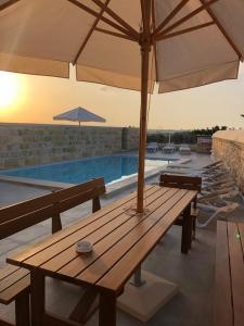 a wooden table with an umbrella next to a pool at Villa Chossie in Żejtun