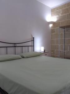 Cama blanca en habitación con pared de ladrillo en Le stanze di Ray, en Borgagne