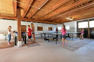 eine Gruppe von Menschen, die in einem Zimmer mit Tischen Tischtennis spielen in der Unterkunft Landhaus Hinterebenhub in Hopfgarten im Brixental