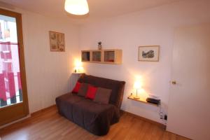 a living room with a couch with two red pillows at Résidence Terrasses d'Etigny in Luchon