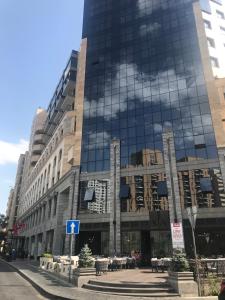 a large glass building with a blue sign in front of it at Byuzand Yerevan Apartment in Yerevan