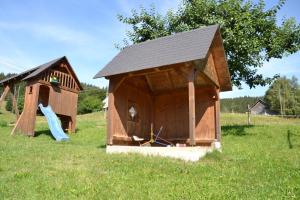 una casa de juegos de madera con un tobogán en un campo en Ferienwohnung beim Pauli en Titisee-Neustadt