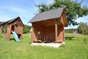 uma casa de jogos de madeira com um escorrega num campo em Ferienwohnung beim Pauli em Titisee-Neustadt