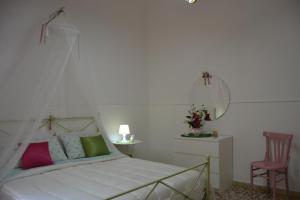 1 dormitorio con cama blanca y silla rosa en Casa Vacanze Montalbano, en Scicli