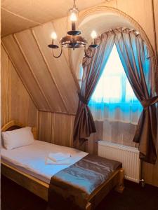 a bedroom with a bed with a large window at Готельно-ресторанний комплекс «Галицький замок» in Ternopilʼ