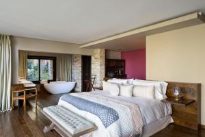 1 dormitorio con 1 cama grande y bañera en Calfuco Wine Hotel & Spa en Villa La Angostura