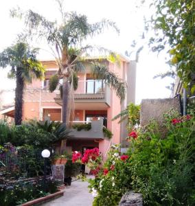 a building with palm trees and flowers in front of it at Route 114 in Acireale