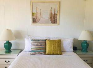 The Ocean Resort Inn في مونتوك: غرفة نوم بسرير مع مصباحين وصورة على الحائط