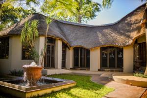 a house with a thatched roof and a fountain at Clivia Lodge in Louis Trichardt