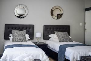 2 Betten in einem Schlafzimmer mit Spiegeln an der Wand in der Unterkunft Clivia Lodge in Louis Trichardt