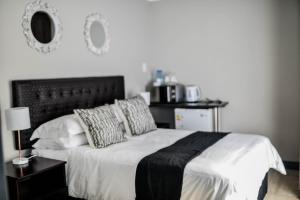 um quarto com uma cama branca e uma cabeceira preta em Clivia Lodge em Louis Trichardt
