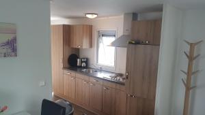 a kitchen with wooden cabinets and a sink and a window at BestMarine Waterchalets Flevo Marina in Lelystad