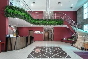 a lobby with a red wall and stairs with plants at Hotel The Premium in Osasco