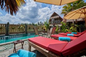 patio ze stołami i krzesłami oraz basenem w obiekcie Royal JJ Ubud Resort & Spa w mieście Ubud