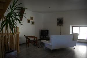 uma sala de estar com um sofá branco e uma cadeira em Le gite du Poisson Roy em Navarrenx