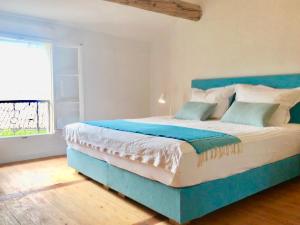 een blauw bed in een kamer met een groot raam bij la bonbonniere - Townhouse Saint-Saturnin-lès-Apt in Saint-Saturnin-dʼApt