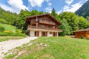 een groot houten huis met een balkon op een veld bij Chalet Clairvaux in Montriond