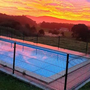 a large swimming pool with a sunset in the background at Apartamentos La Pradera de Isla in Isla