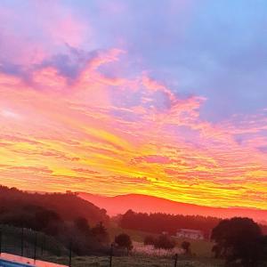 a sunset in a field with a sky at Apartamentos La Pradera de Isla in Isla