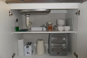 a kitchen shelf with dishes and other items on it at Rosy Palm Sunrise in Upington