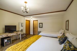 a hotel room with a bed, television and a desk at Pousada Da Pedra in Campos do Jordão