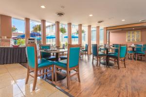 un comedor con mesas, sillas y ventanas en Coast Discovery Inn, en Campbell River