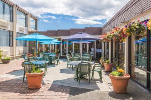 un patio con mesas y sillas y sombrillas azules en Coast Discovery Inn en Campbell River