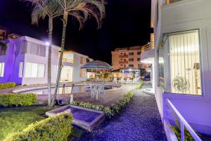 a building with a patio with a table and palm trees at Oceanic Lodge in Tonsupa