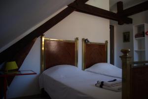 um quarto com 2 camas com lençóis brancos e uma cabeceira em madeira em Le gite du Poisson Roy em Navarrenx