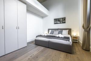 a bedroom with a bed with white walls and wooden floors at Elegant Fornasa Vecia, canal view with a beautiful garden R&R in Venice