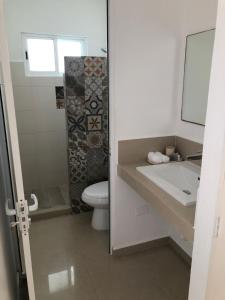 a bathroom with a sink and a toilet and a mirror at Playa 55 beach escape - adults only Guesthouse in Celestún