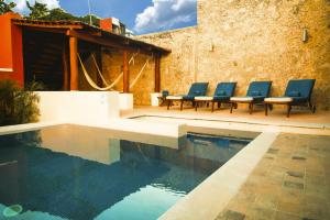 een zwembad met blauwe stoelen naast een gebouw bij Hotel Boutique Casa Don Gustavo, Campeche in Campeche