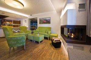 un soggiorno con sedie verdi e camino di Pension Angelika a Pettneu am Arlberg