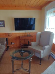 a living room with a chair and a table and a tv at Gite les 2 Soeurs in Roberval