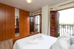 1 dormitorio con cama blanca y balcón en Aljibe Albaicín House by A3Rentals, en Granada
