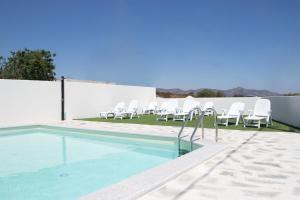 a swimming pool with white chairs next to a fence at Mediterraneo in San Teodoro