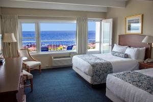 グロスターにあるAtlantis Oceanfront Inn Gloucesterのベッド2台が備わる海の景色を望むホテルルームです。