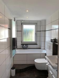 a bathroom with a tub and a toilet and a window at Ferienwohnung Mentes in Füssen