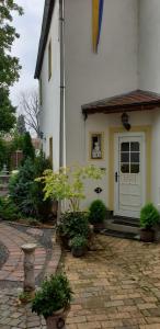 una casa blanca con una puerta blanca y algunas plantas en Gartenblick Delitzsch en Delitzsch