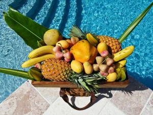 a basket of fruit on a table next to a pool at Bequia Beach Hotel - Luxury Resort in Friendship