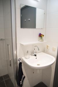 a white bathroom with a sink and a mirror at Kerkovernachting in Schettens
