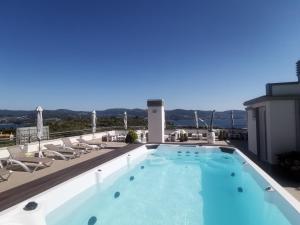 a swimming pool on the roof of a building with chairs at Hotel Ancora SANXENXO in Granxa