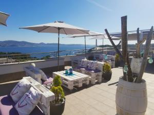 une terrasse avec des chaises, des tables et un parasol dans l'établissement Hotel Ancora SANXENXO, à Granxa