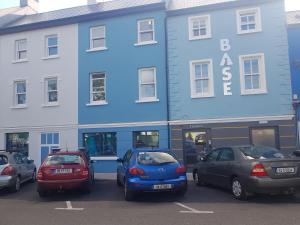 um grupo de carros estacionados em frente a um edifício azul em Base Dingle em Dingle