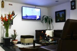 sala de estar con sofá y TV en la pared en Hotel Royal Suite, en Manizales