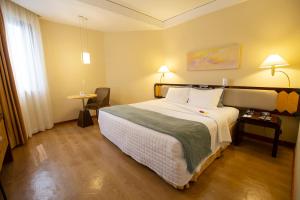 a hotel room with a large bed and a table at Golden Tower Pinheiros by Fênix Hotéis in São Paulo