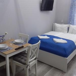 ein Schlafzimmer mit einem Bett und einem Tisch mit einer blauen Decke in der Unterkunft Apartamenty Przystań in Misdroy