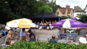 a group of people sitting at tables under umbrellas at Winchester Arms in Trull